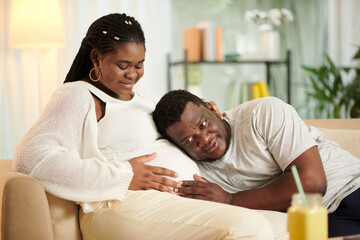 Fototapeta premium Man putting ear to bump of his pregnant wife to listen to babys heartbeat