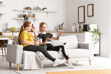 Sporty young women sitting on sofa at home