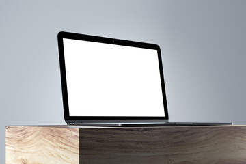 Close up of empty white laptop monitor on wooden surface and gray wall background. Product presentation and advertisement concept. Mock up, 3D Rendering.