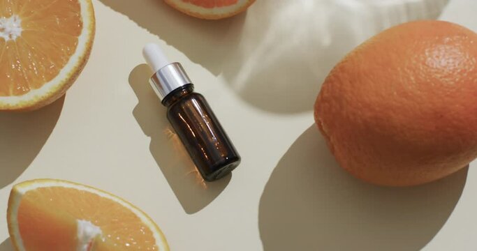 Video of make up bottle with pipette, citrus slices and copy space on yellow background