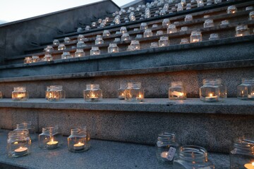 Many lighted candles in glass clear glasses are located on the stairs