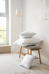 Grey bench with pillows and standard lamp near white wall