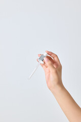 Asian female hand holding a cosmetic dropper in hand.