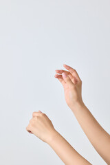 A asian female hand holding a cosmetic dropper in her hand and making a gesture as if dropping it on the back of her hand.