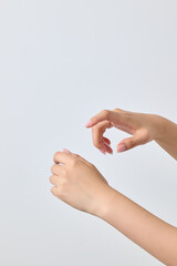 A asian female model's gesture as if she were squeezing a lotion-like pump-type cosmetic product onto the back of her hand.