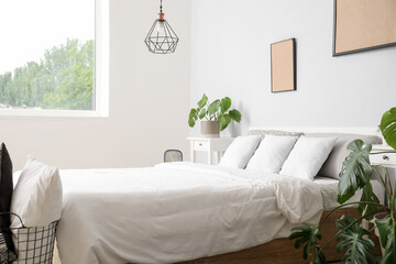 Interior of modern bedroom with comfortable double bed, white pillows and houseplants
