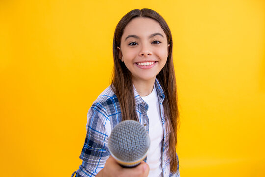 teen girl singer interviewing in studio. young girl singer perform karaoke isolated on yellow background. With microphone in hand teenage girl singer. young karaoke singer girl hold microphone