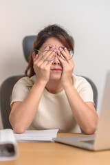 Stressed Asian woman having Tired and Sleepy while working, female businesswoman using laptop with headache at office, Exhausted woman with computer at home late night. Overload and Overworked
