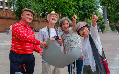 Group of seniors enjoy visiting Chiang Mai's old town with rough map. Elder group travel happily with map tor discover old town. Vacation and travel concept.