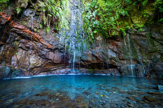 Scenic view of the lagoon at the end of the Levada das 25 Fontes hiking trail, where a waterfall cascades down the overgrown cliffs, Madeira, Portugal