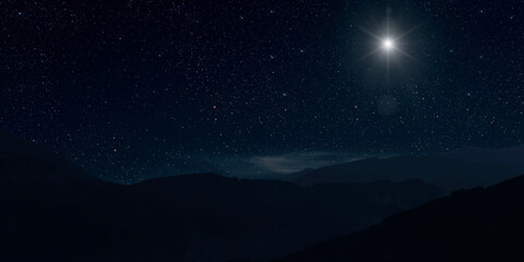 Fototapeta na wymiar a Christmas star shines at night over the mountains of Bethlehem