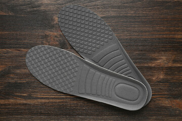 Pair of orthopedic insoles on dark wooden background