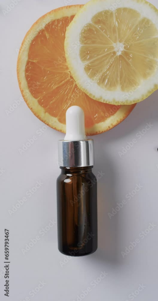 Poster vertical video of make up bottle with pipette, citrus slices and copy space on white background