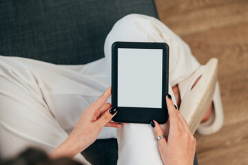 Young woman sitting the couch with an e-book