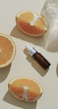 Vertical video of make up bottle with pipette, orange slices and copy space on white background