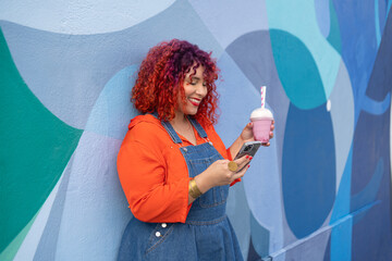 Happy femele with colour hair holding milk cocktail and smartphone