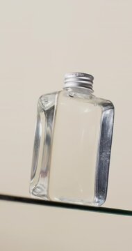 Vertical video of beauty product bottle on glass shelf with copy space on white background