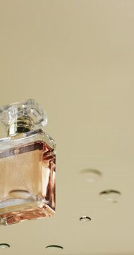 Vertical video of drops falling on beauty product bottle with copy space on yellow background