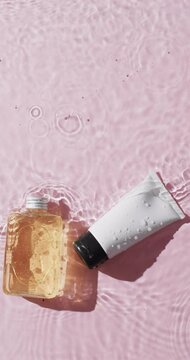 Vertical video of beauty product tube and bottle in water with copy space on pink background