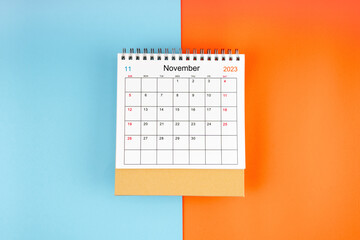 The Directly above view of November 2023 desk calendar on blue and orange background with copy space.