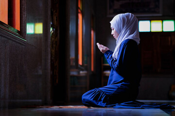 Muslim woman praying for peace from Allah, Muslim God, at room near window Muslim woman's hands on prayer rug in traditional dress, woman in hijab,