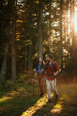 A multicultural pair with backpacks and walking sticks discover the beauty of the outdoors, their beaming smiles mirroring their excitement for the journey ahead