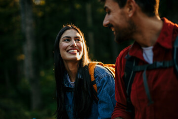 A diverse couple with backpacks and hiking poles eagerly explore the great outdoors, reveling in the serenity and beauty of their surroundings