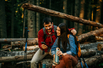 A mixed couple sits together on a sturdy log, radiating a sense of accomplishment and mutual...