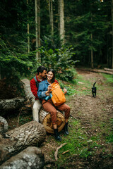 Naklejka na ściany i meble A multicultural couple, their backpacks leaning against the log, unwind and share a tender moment after conquering a rugged trail