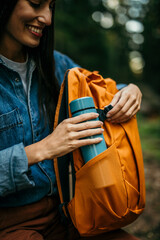 Young woman rehydrating after a challenging hike, sitting on a log surrounded by lush greenery