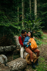Naklejka na ściany i meble A diverse couple, their backpacks suggesting a day of exploration, relaxes on a wooden log, cherishing the memories made during their outdoor escapade