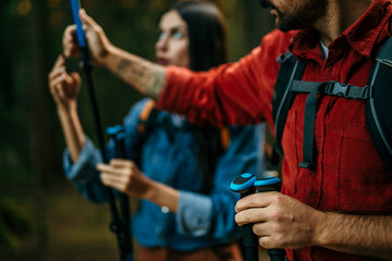 A multicultural pair, beaming with excitement, embarks on a scenic hike surrounded by lush greenery, their backpacks and trekking poles ready for the journey ahead