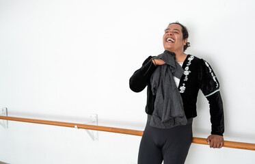 confident young male dancer smiling while resting and leaning on the ballet barre, attractive plus sized african american man laughing