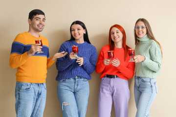 Group of friends with glasses of mulled wine on beige background