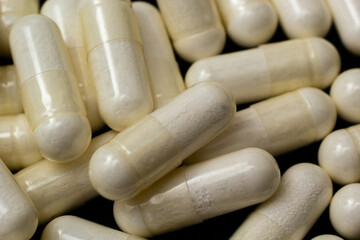 White capsules, pills on a black background. Medicine, healthcare concept. Range of pharmaceutical drugs