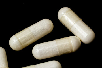White capsules, pills on a black background. Medicine, healthcare concept. Range of pharmaceutical drugs