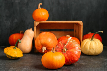 Wooden box with different fresh pumpkins on black background