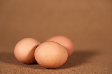 Three brown chicken eggs Isolated on a brown background