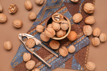 Bowl with walnuts and nutcracker on brown background