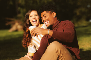 Young couple enjoying a park on a sunny day and drinking coffee