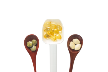 Top view variety of vitamins, minerals, and fish oil in pill form on a wooden spoon isolated onwhite or transparent cutout background. Dietary food supplements are a new alternative to health care.