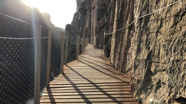 Dolly shot of wooden platform and chairs along rocky cliff in Caminito del Rey, El Chorro, Spain.