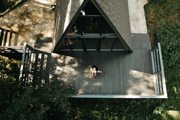 Fototapeta premium Young Woman relaxing and meditating in a house in the forest in autumn. Retreat and meditation concept