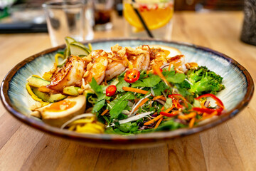 Sweet and sour salad, boiled egg and shrimp with chilli on plate, drink on restaurant table.