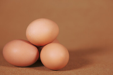 Three brown chicken eggs Isolated on a brown background