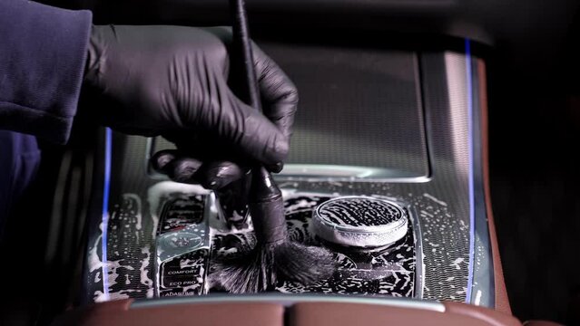 Men's manual cleaning of the interior and upholstery of the car with a brush for parts. The concept of detailing the car. Car wash background.
