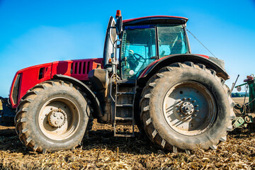 Tractor in the field. Agricultural machinery. Agricultural farm tractor during tillage of soil and field after harvest.