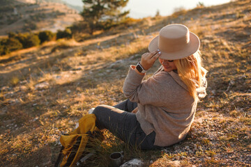 Back view of the plus size woman rests in the mountain. The girl admires beautiful views of landscape. Travel and tourism. Hiking. The overweight woman holding yellow bagpack