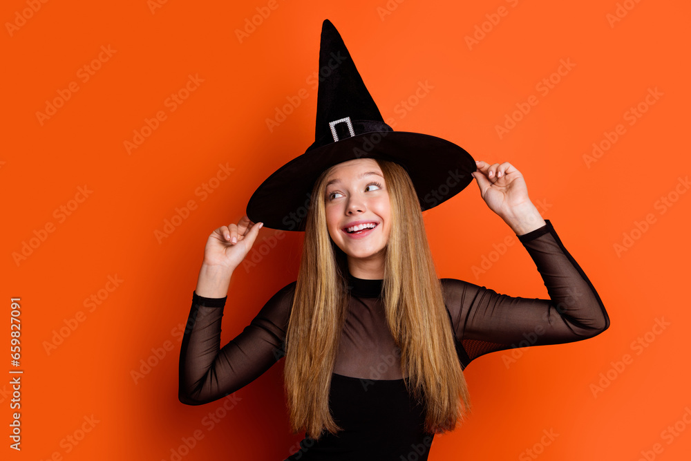 Sticker photo of charming positive teen girl arms touch enchant hat look empty space ad isolated on orange c