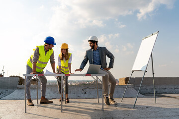 Construction concept. Engineers and architects working at construction site with blueprint